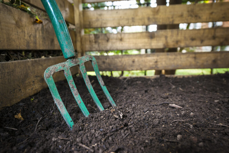 Garden,Fork,Turning,Black,Composted,Soil,In,Wooden,Compost,Bin Garden,Fork,Turning,Black,Composted,Soil,In,Wooden,Compost,Bin